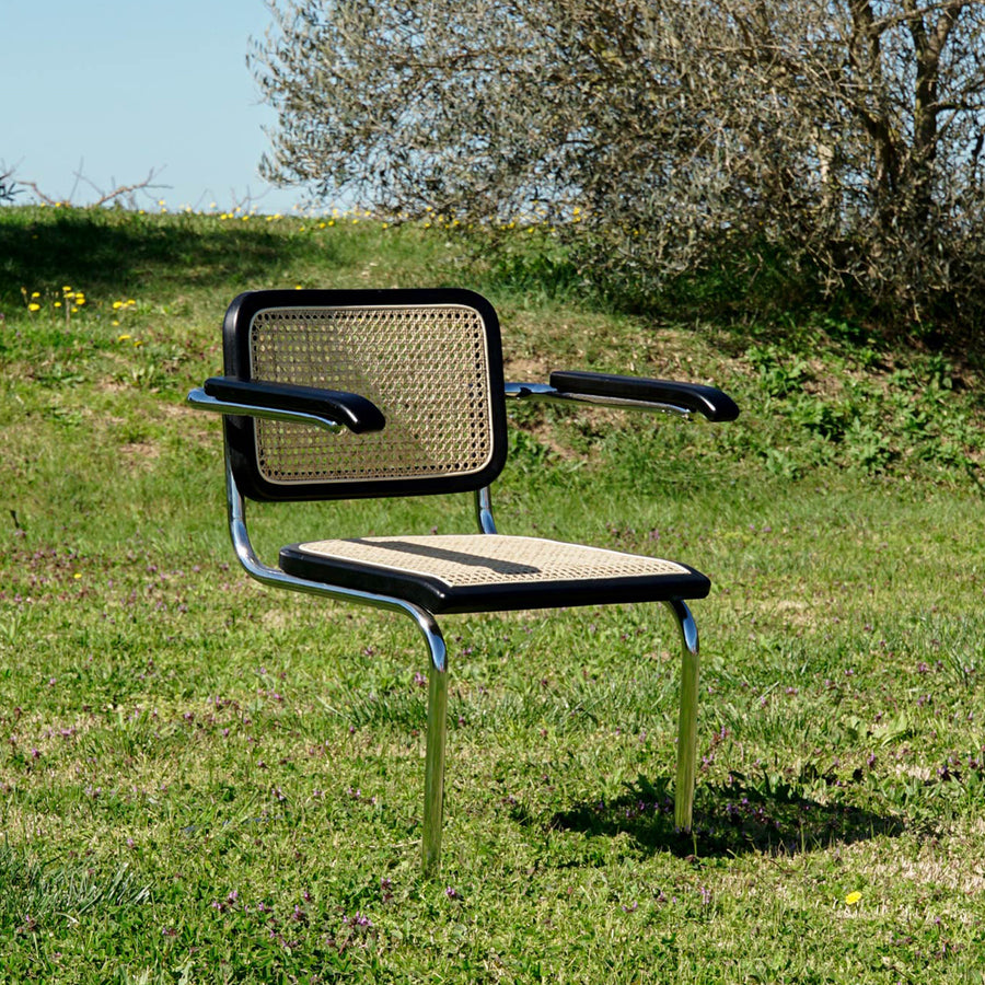 Modern fémvázas, fekete színű, rattan betétes karosszék.