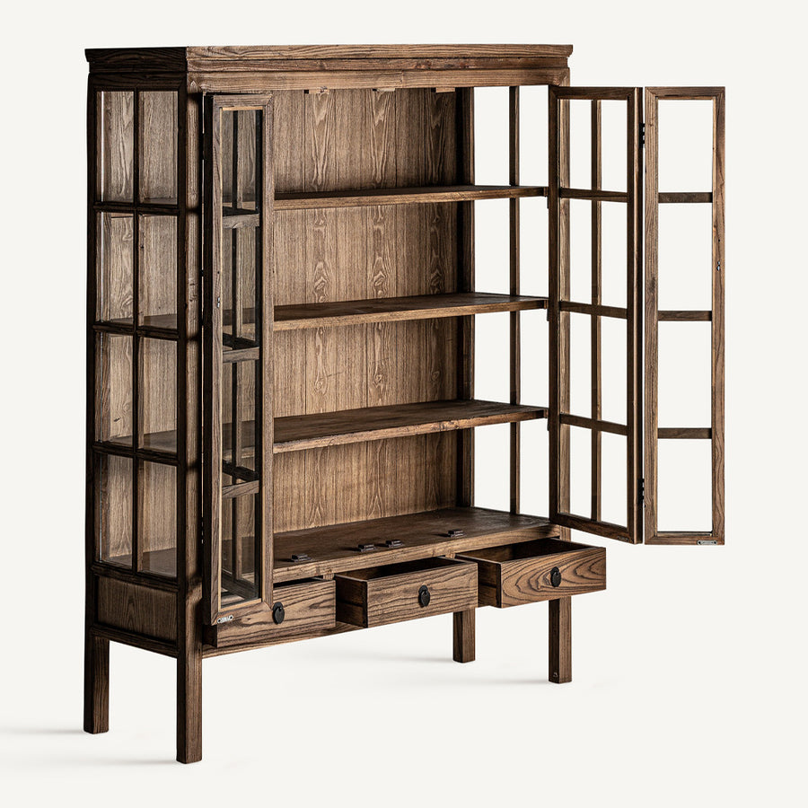 Koloniál ihletésű, natúr színű, pácolt felületű szilfából készült, 2 ajtós és 3 fiókos vitrines szekrény.