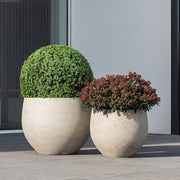 Betonhatású kaspók kültéren, modern épület előtt, zöld és piros növényekkel beültetve – Pottery Pots Urban kollekció