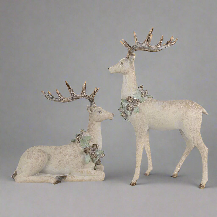 Tobozkoszorúval díszített, bézs színű, karácsonyi szarvas figura.