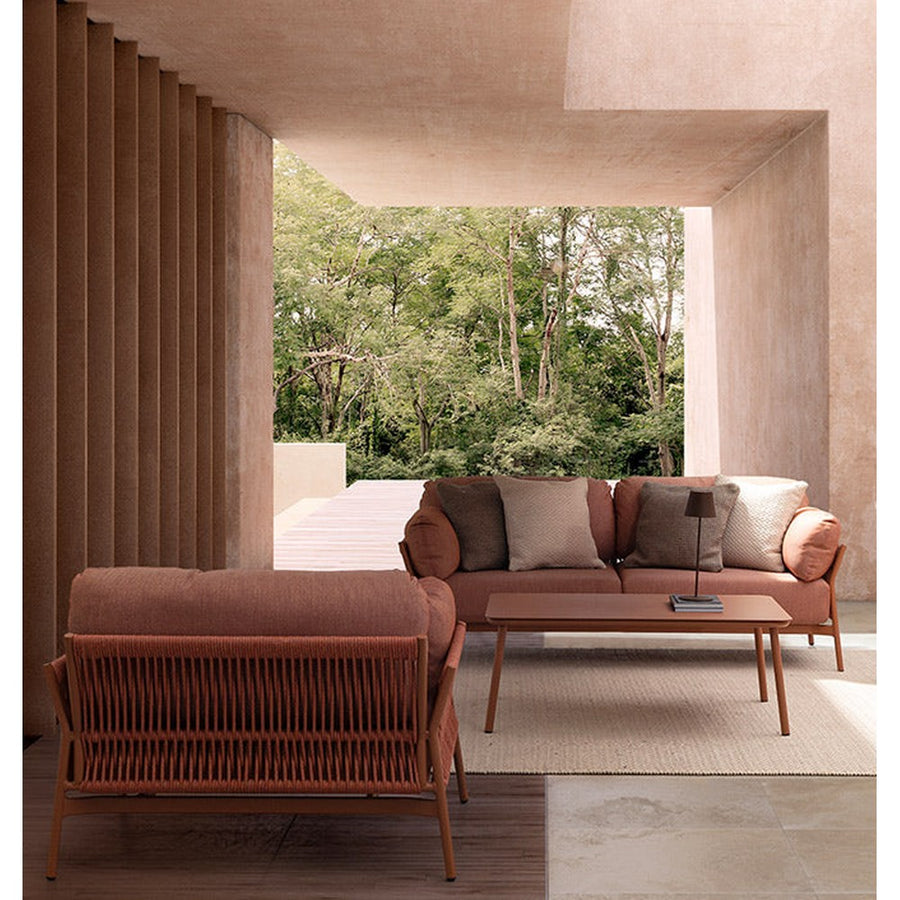 Fedett, mediterrán teraszon álló kortárs, korallszínű kanapé és fotel.