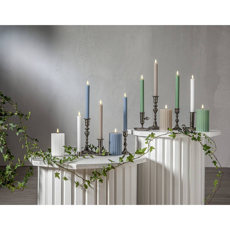Stripe LED gyertya kollekció különböző méretű és színű valódi viaszból készült kannelúrás gyertyákkal, vintage gyertyatartókban elhelyezve, meleg fényű LED lánggal.