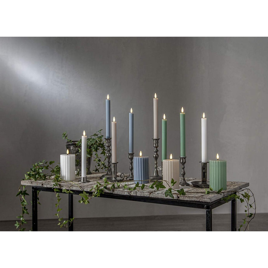 Stripe LED gyertya kollekció különböző méretű és színű valódi viaszból készült kannelúrás gyertyákkal, vintage gyertyatartókban elhelyezve, meleg fényű LED lánggal.