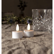 2 darabos LED gyertya, üvegpoharakkal asztalon. 