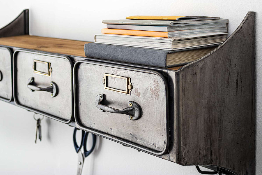 Fémből és fából készült, 83 cm hosszú és 30 cm magas, 3 fiókos, antikolt szürke színű, fogassal ellátott, ipari stílusú szortírozó falipolc könyvekkel.