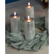 4 darabos, élethű megjelenésű, ezüstszínű, valódi viaszból kialakított, időzítővel rendelkező, távirányítós, dimmelhető, 15 cm magas LED oszlopgyertya, fenyőkoszorún.