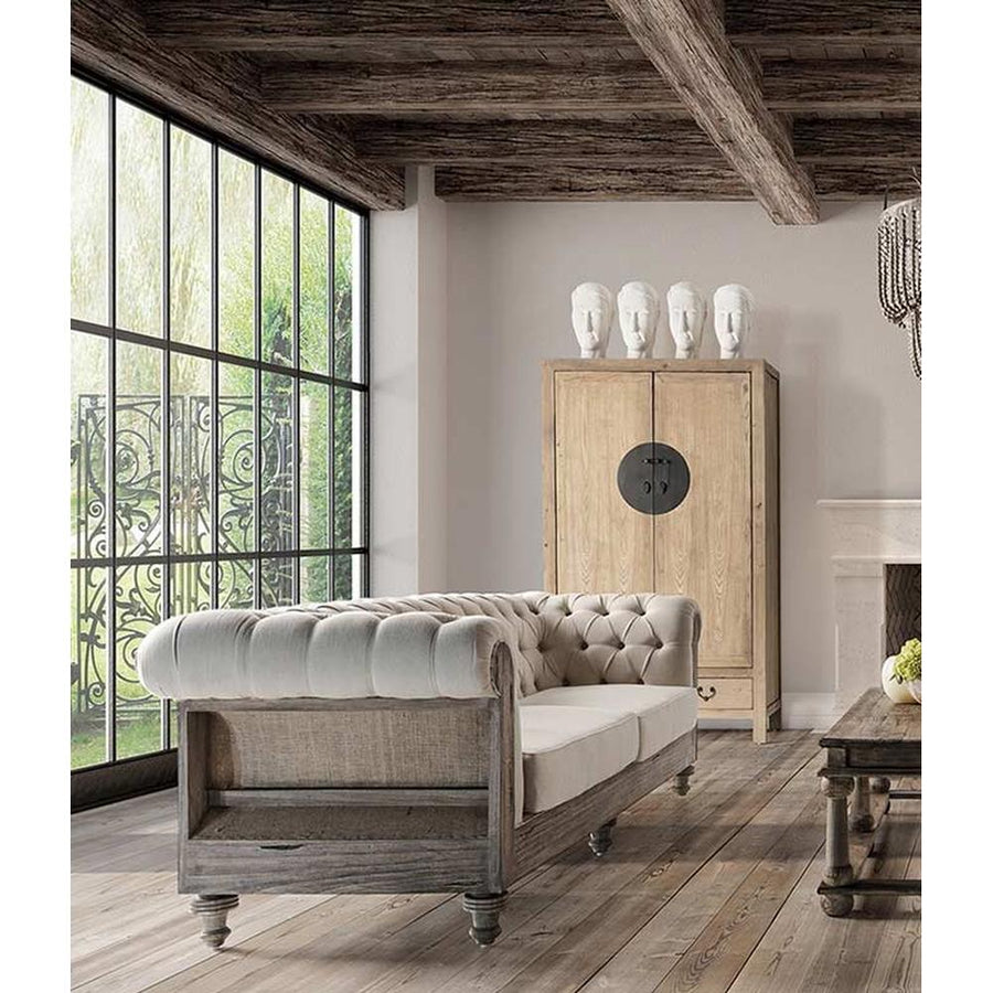 Prémium kategóriás, gyarmati stílusú, újrahasznosított trópusi fából készült, nagy méretű, 4 személyes, tört fehér színű szövettel kárpitozott kanapé  vidéki stílusú nappaliban, hatalmas osztott üvegű ablak előtt, deszka padlón., gerendás mennyezettel. 