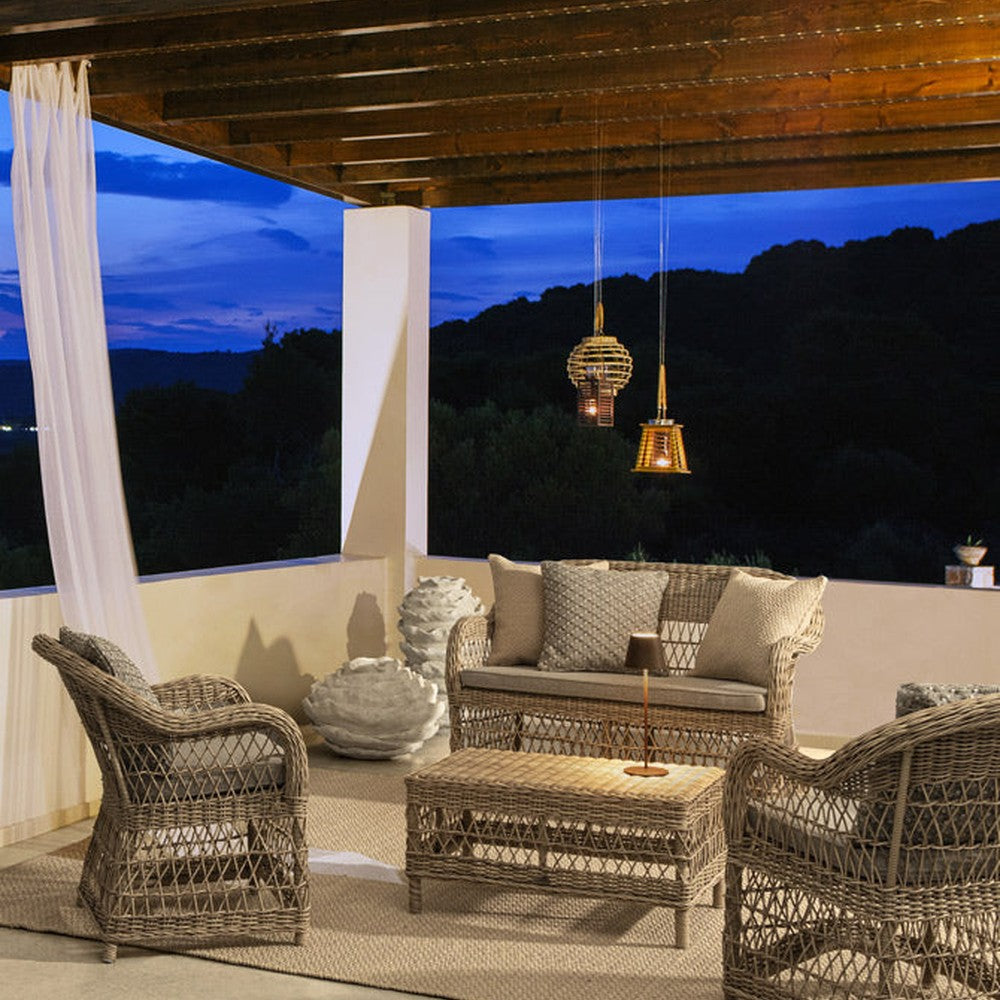 Mediterrán teraszon álló vintage stílusú, négyrészes, natúr színű műrattan kerti ülőgarnitúra.