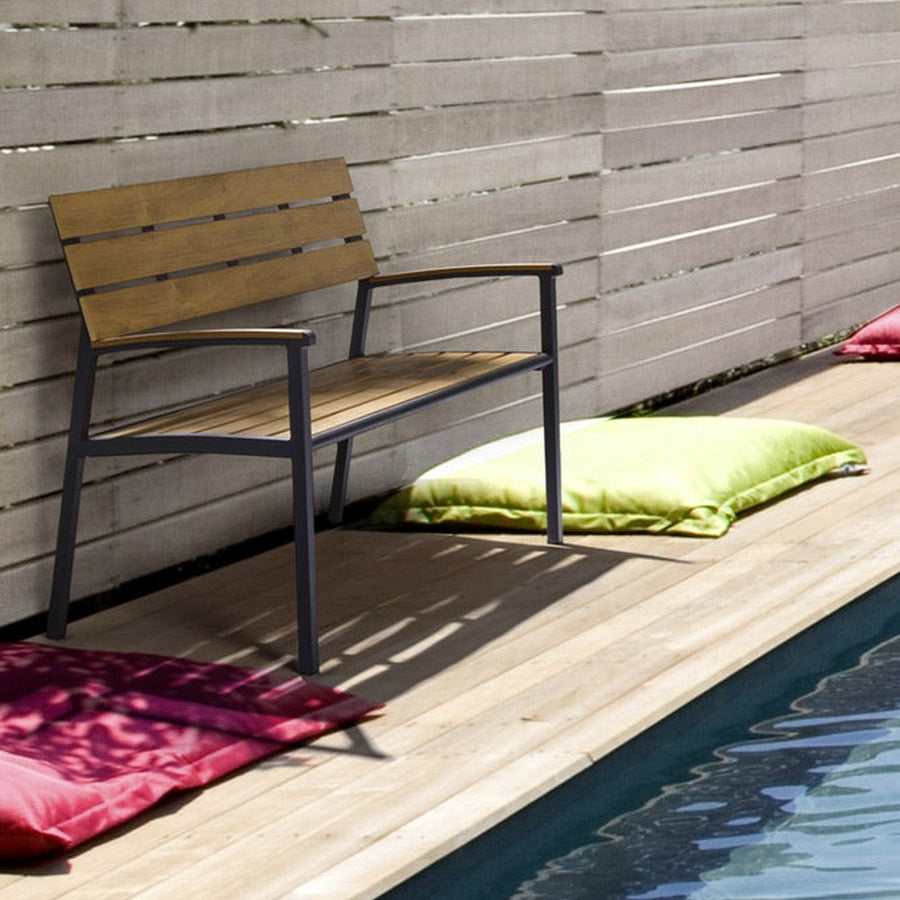 Medence szélén álló fémvázas kerti pad.