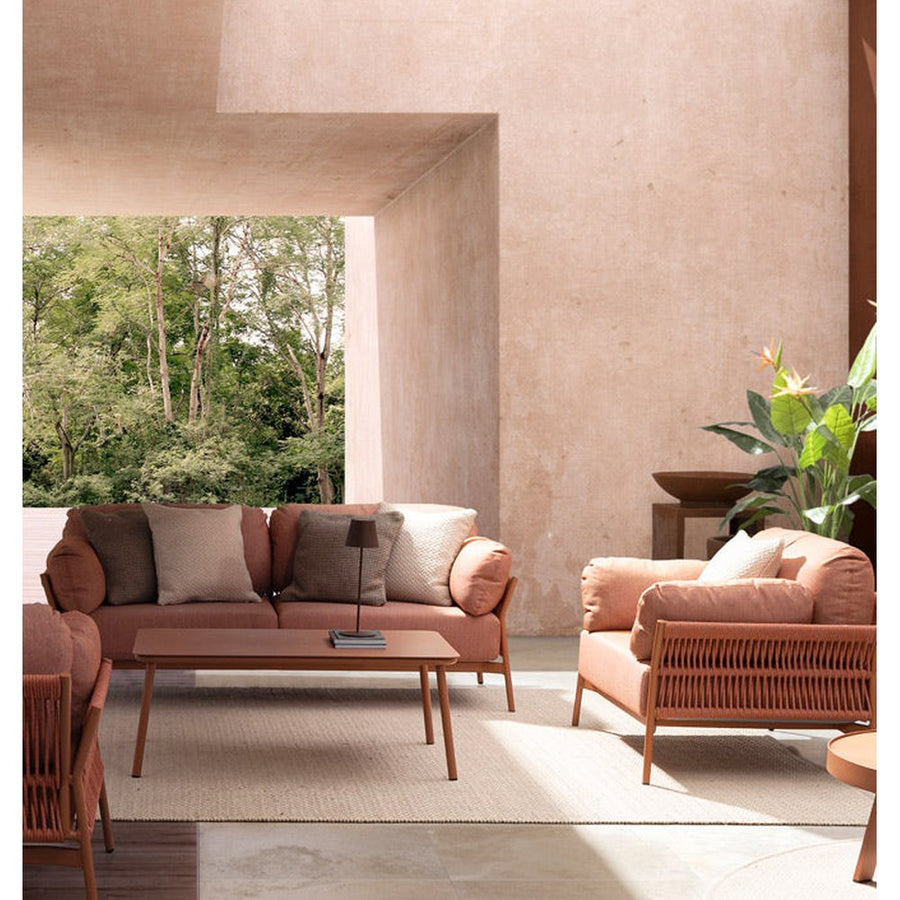 Fedett, mediterrán teraszon álló kortárs, korallszínű kanapé és fotelek és dohányzóasztal.