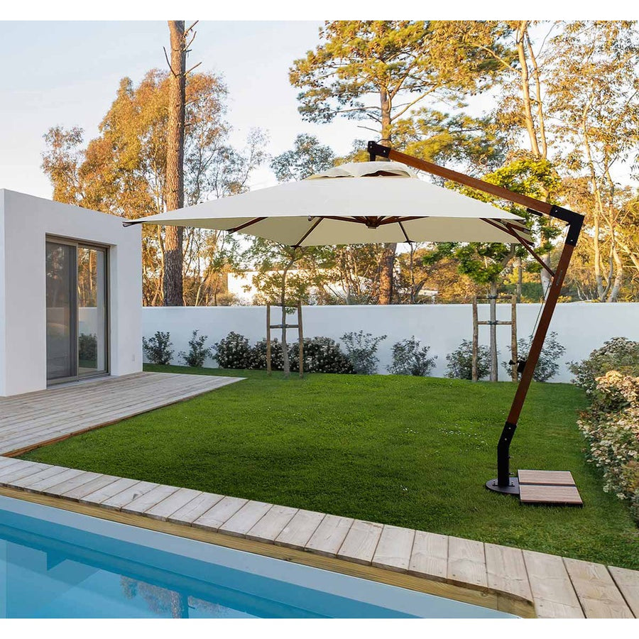 Füves udvaron, medece mellett álló teakfa vázas szövet napernyő.