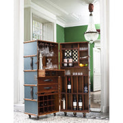 Fényűző nappaliban felállított utazási bőrönd formájú bárszekrény poharakkal, italokkal, gyümölcsökkel.