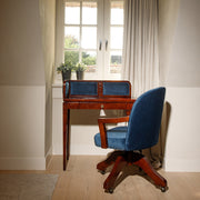 Közlekedőben álló bársonyberakásos panellel rendelkező íróasztal székkel.