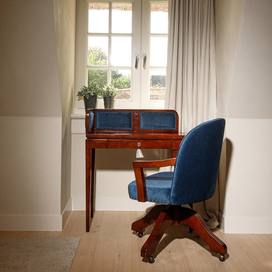 Közlekedőben álló bársonyberakásos panellel rendelkező íróasztal székkel.