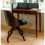 Hálószoba ablaka előtt álló bársonyberakásos panellel rendelkező íróasztal.