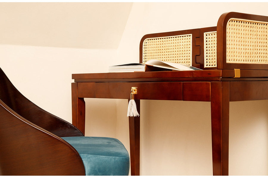 Szoba sarkában álló rattanberakásos árnyékoló panellel rendelkező íróasztal székkel.