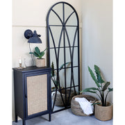 Loft stílusú szobában, komód valamint kosarak melett álló loft stílusú, fekete színű falitükör.