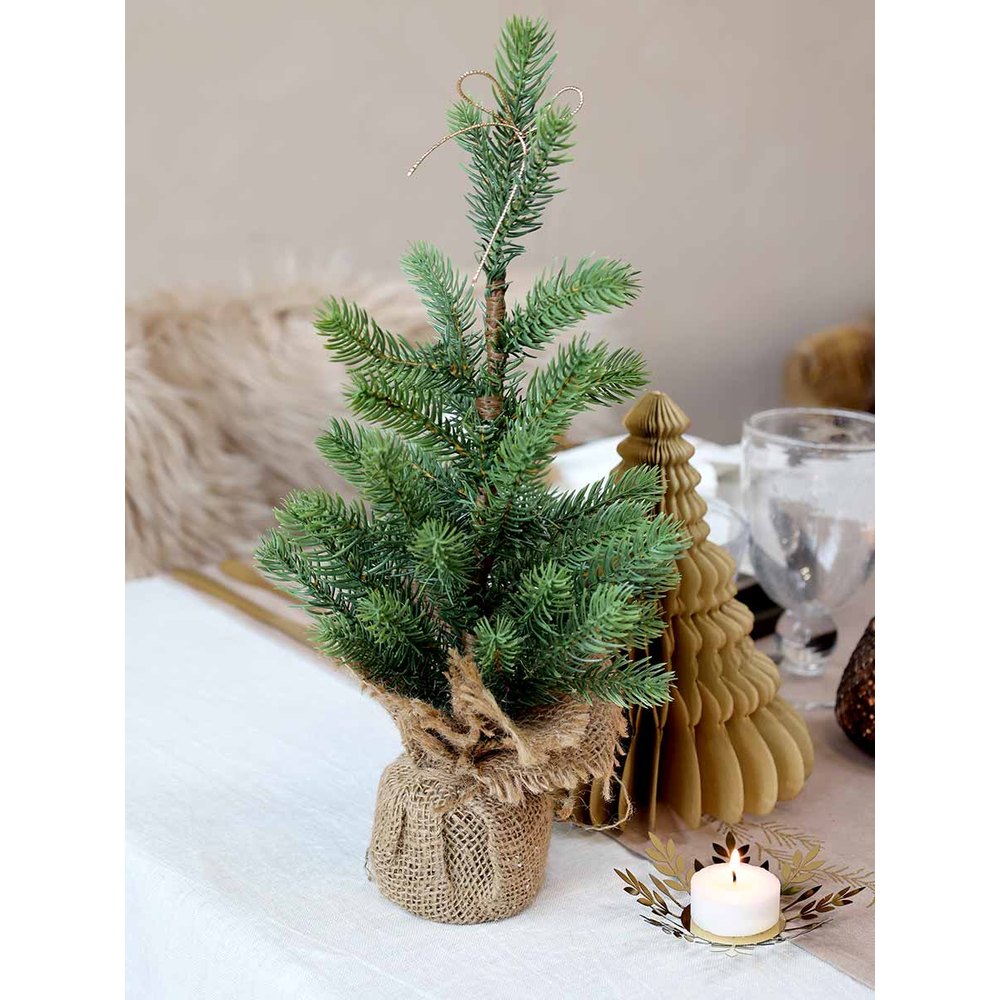 Karácsonyi asztalt díszítiő, élethű, kisméretű deko fenyőfa jutazsákban.
