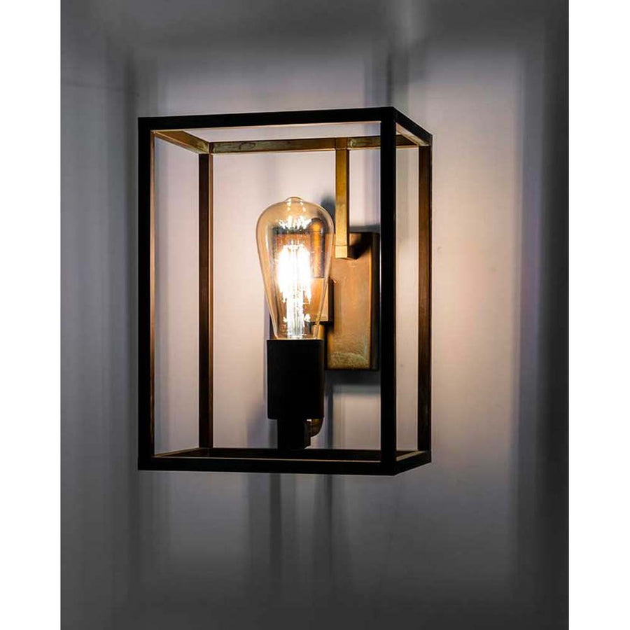 Ipari stílusú, rézből készült falilámpa, téglatest alakú keretben működés közben.