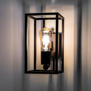 Industrial stílusú, rézből készült, matt fekete színű falilámpa működés közben.