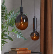 A Colourmix termékcsalád narancssárga izzói egy kisasztal felett lógnak.