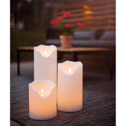 Kültéri terasz padlóján álló, három különböző méretű fehér színű LED gyertya.