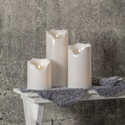 Élethű, meleg fehér fényű, fehér színű LED gyertyák kültéri padon.