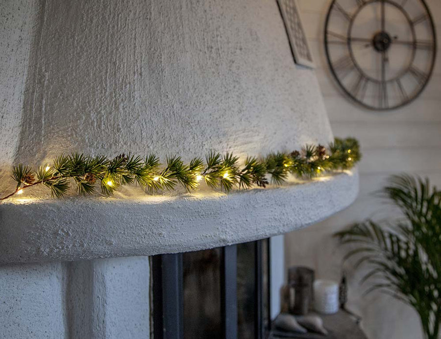 LED-es vörösfenyő girlanddal díszített karácsonyi kandalló.