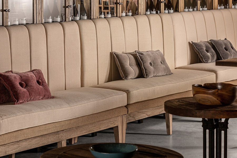 Rusztikus hangulatú borászatban, egymás mellett álló koloniál kanapék díszpárnákkal.