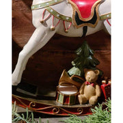 Vintage stílusú, 29,5 cm hosszú, fehér és piros színű karácsonyi hintaló ajándékokkal barna deszkafal előtt 