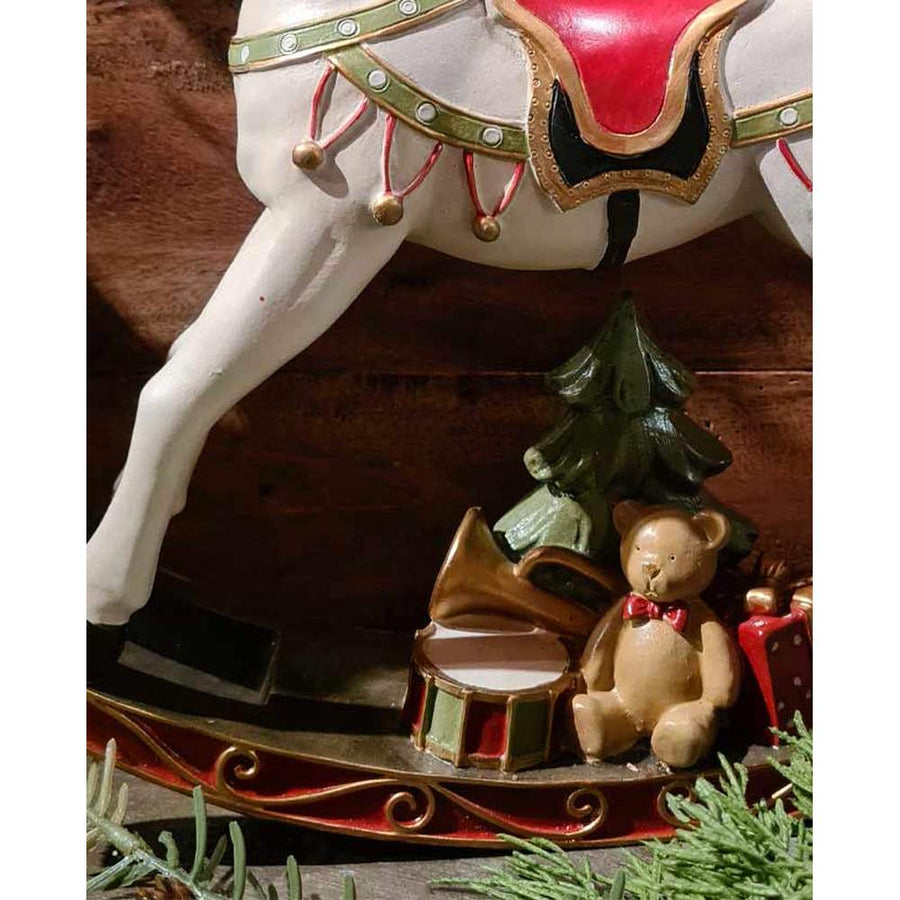 Vintage stílusú, 29,5 cm hosszú, fehér és piros színű karácsonyi hintaló ajándékokkal barna deszkafal előtt 