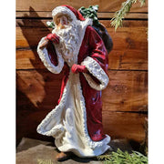 Vintage stílusú, békebeli klasszikus tálapó, mikulás figura bordó kabátban puttonnyal a hátán antikolt barna deszka előtt 