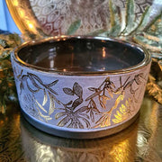 Aranyszínű dombormintával díszített, modern, glamour stílusú kerámia arany tál, aranyszínű fém tálcán.