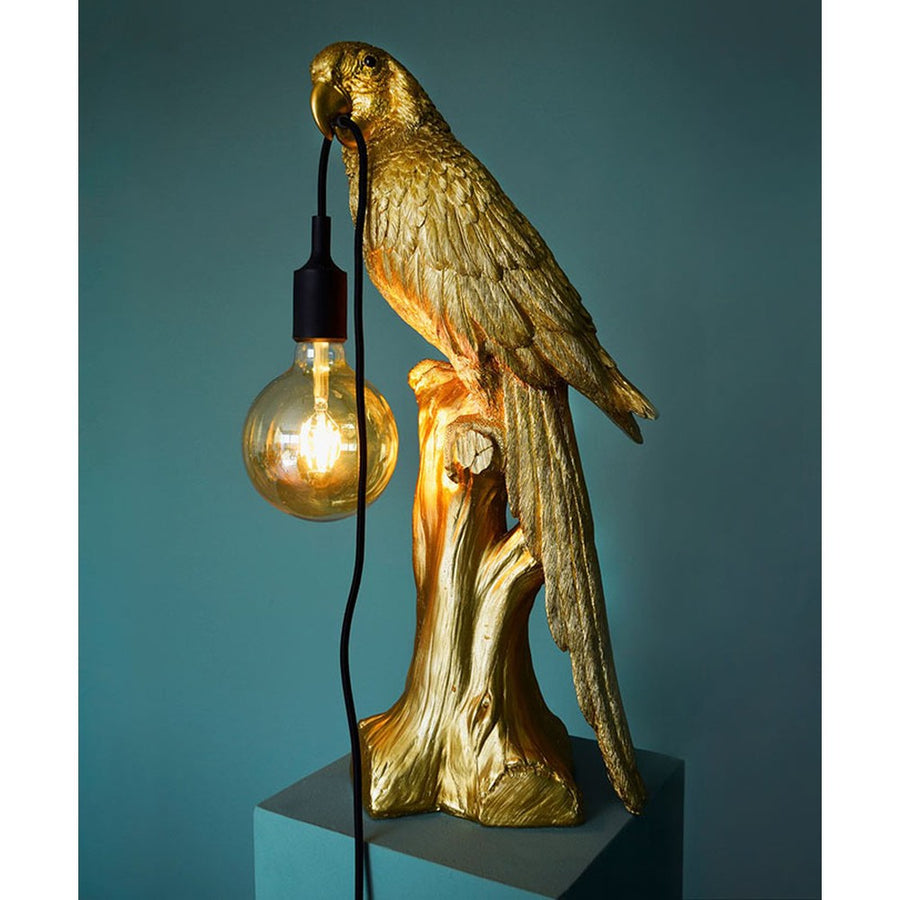 Aranyszínű papagáj figurás, 61 cm magas, trópusi, glamour stílusú asztali lámpa, szürkéskék háttér előtt.
