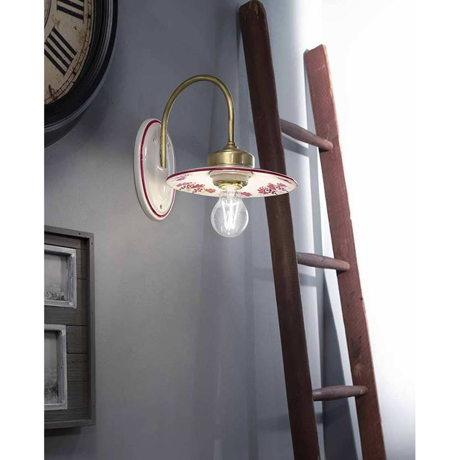 Festett motívumokkal díszített, mázas kerámiából és fémből készült kézműves falilámpa.