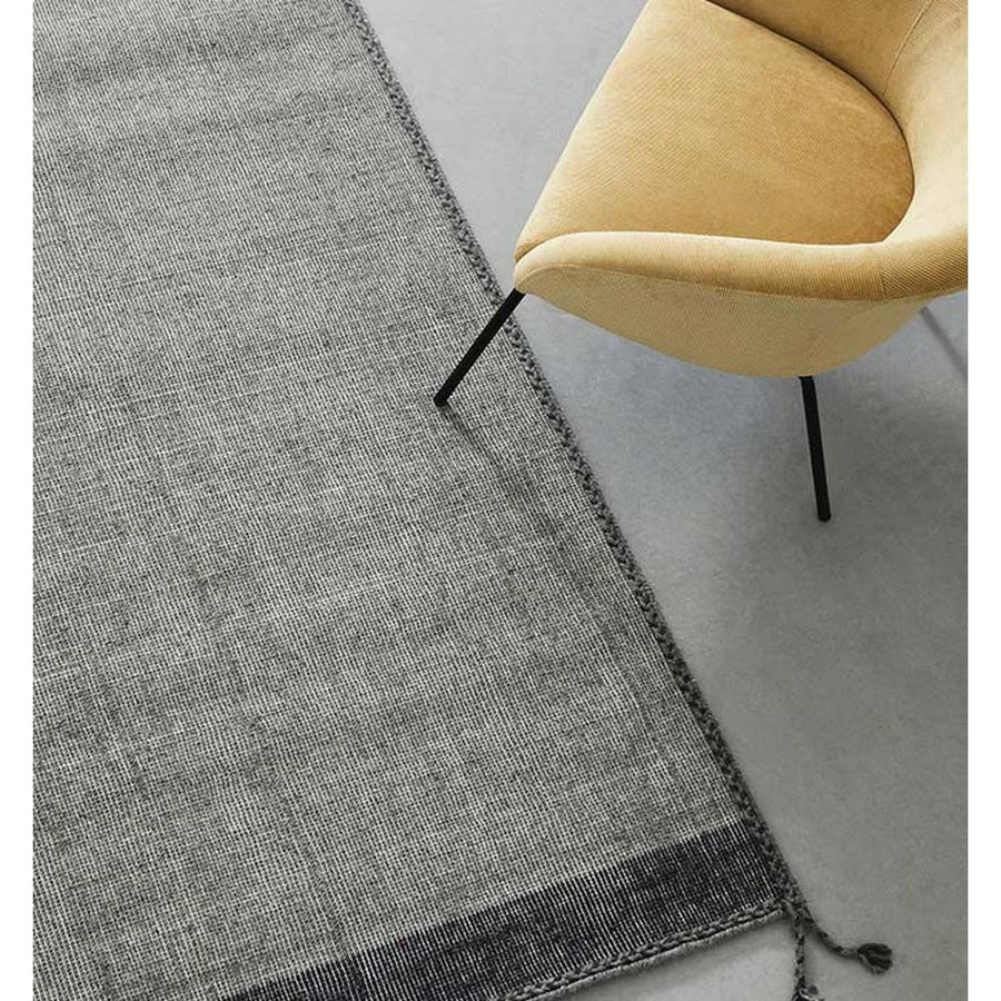 Szürke színű gyapjú szőnyeg, sárga fotellel.