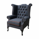 Narancssárga színű szegélyű, sötétszürke színű vászonnal kárpitozott Chesterfield fotel.