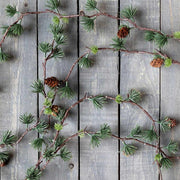 Tobozokkal díszített mű karácsonyi cédrus fenyő girland szürke színű deszka falon.