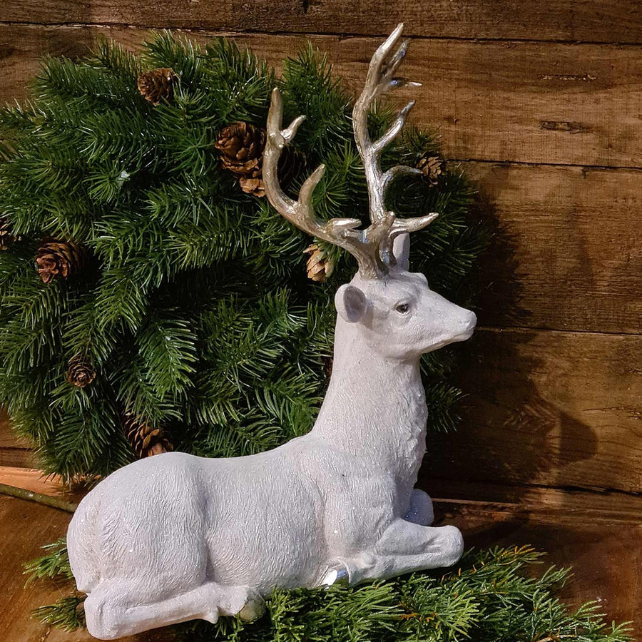 Glamour stílusú, fehér színű, deres hatású, ezüst agancsú és patájú exkluzív karácsonyi szarvas..
