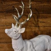 Glamour stílusú, fehér színű, deres hatású, ezüst agancsú és patájú exkluzív karácsonyi szarvas.