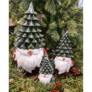 Karácsonyi manók fenyősapkában, zöld fenyők között.