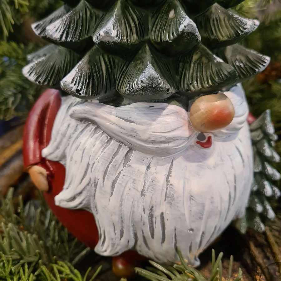 Karácsonyi manó fenyősapkában, zöld fenyők között.