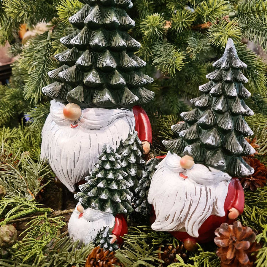 Karácsonyi manók fenyősapkában, zöld fenyők között.