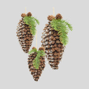 Fenyőággal és apró tobozokkal díszített, havas felületű, függeszthető karácsonyi toboz dísz.