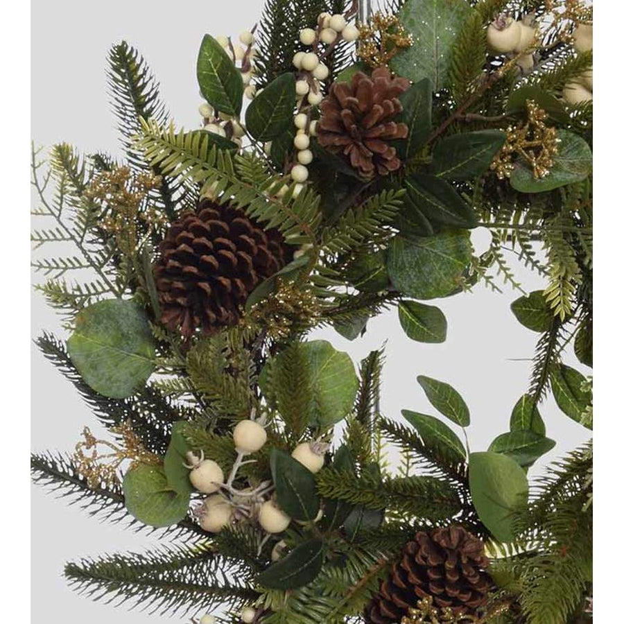 Karácsonyi koszorú, fenyőágakból és eukaliptuszokból, fenyőtobozokkal és fehér erdei bogyókkal díszítve.