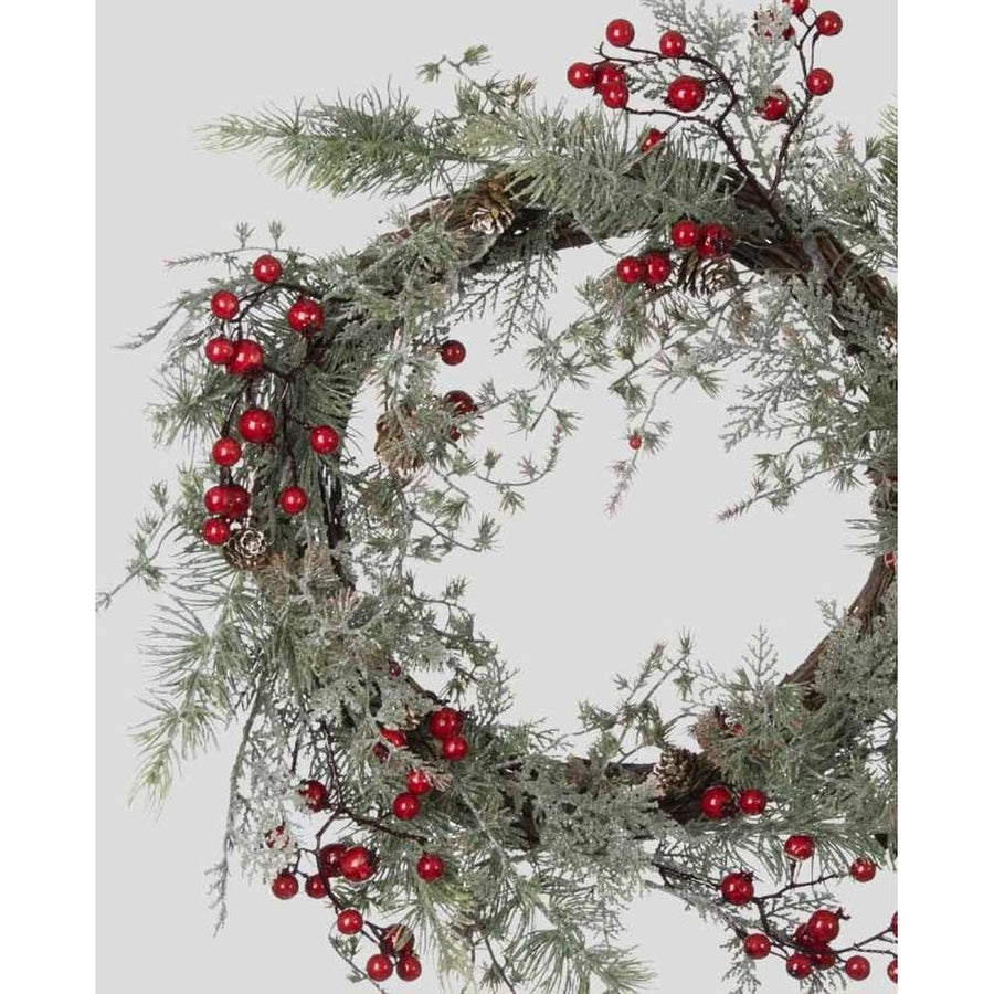 Piros bogyókkal díszített, ezüstös zöld színű mesterséges fenyőágakból készült karácsonyi koszorú, ajtódísz.