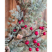 Piros bogyókkal díszített, ezüstös zöld színű mesterséges fenyőágakból készült karácsonyi koszorú, ajtódísz.