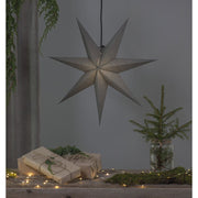 Szürkeszínű, karácsonyi papírcsillag lámpa szürke háttér előtt, fenyőágakkal.