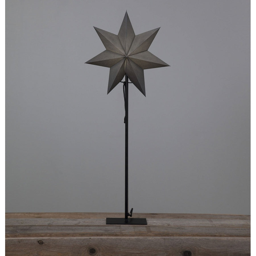 Szürkeszínű karácsonyi pípírcsillag fém talapzaton, natúr fa asztalon. 