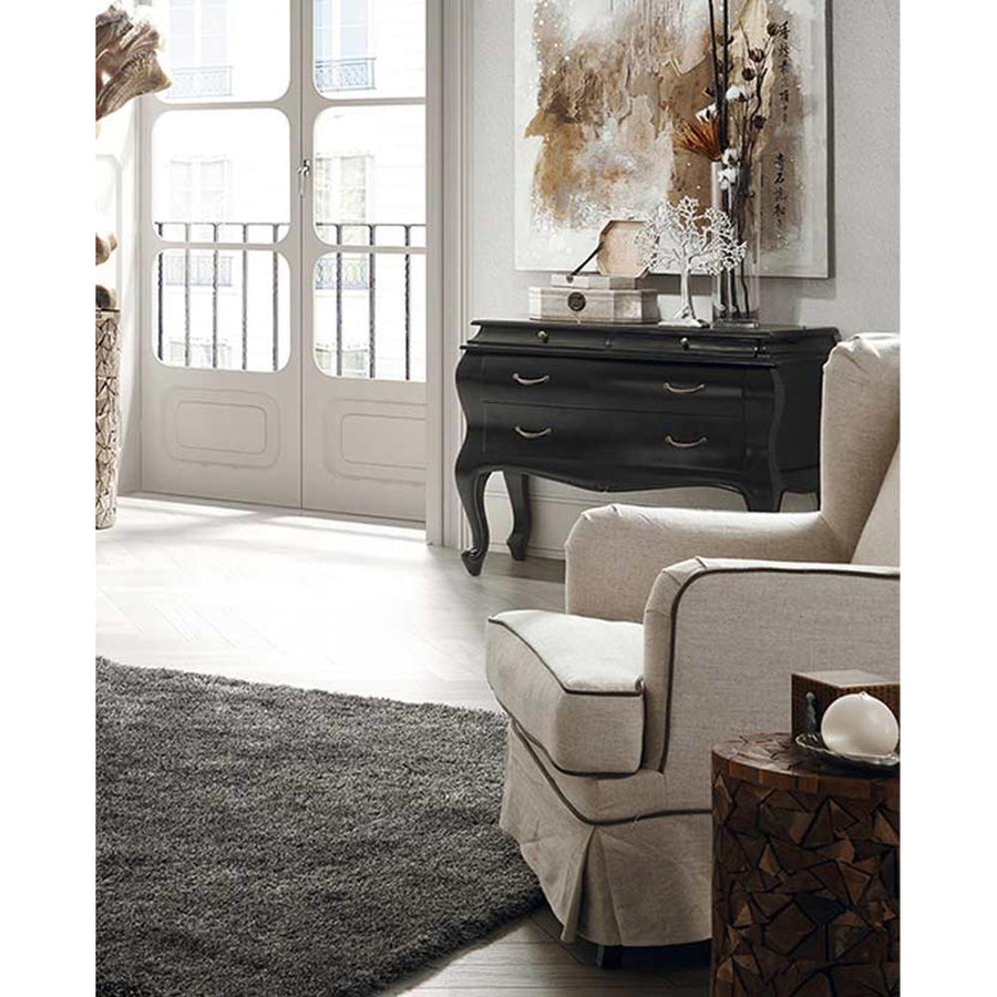 Fekete színű mahagónifa komód bézs fotellel, világos szobában. 